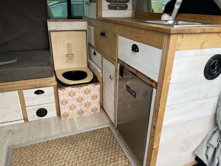 Intérieur d'un van aménagé avec cuisine et toilettes.