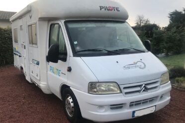 Camping-car Pilote blanc garé sur allée gravillonnée.