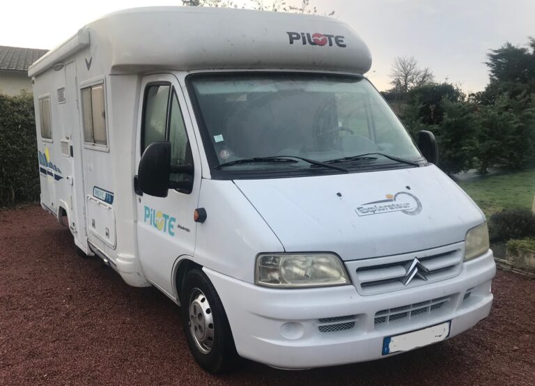 Camping-car Pilote blanc garé sur allée gravillonnée.