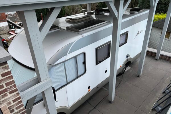 Camping-car garé sous un abri en bois.