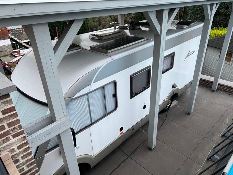 Camping-car garé sous un abri en bois.