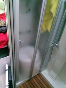 Douche compacte avec paroi vitrée et pommeau argenté.