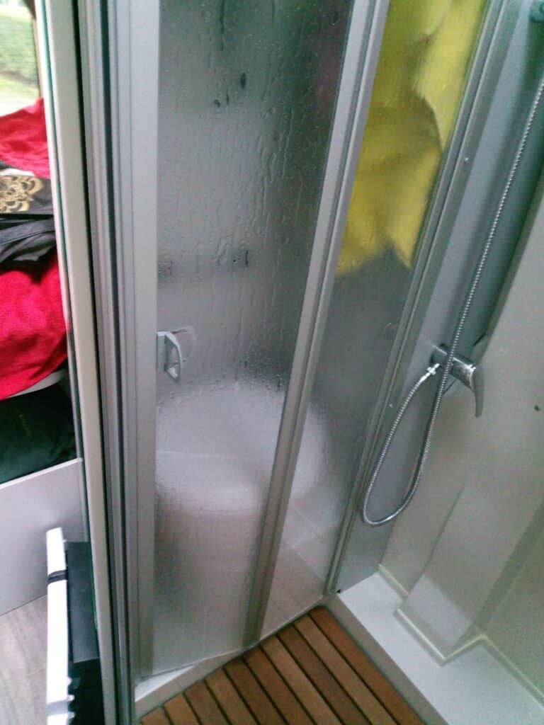 Douche compacte avec paroi vitrée et pommeau argenté.