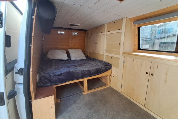Intérieur confortable de fourgonnette aménagée avec lit cosy.