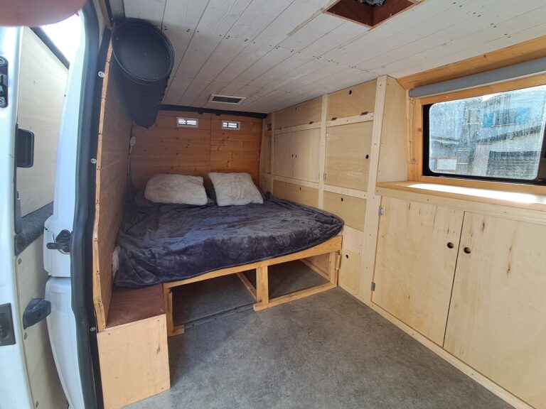 Intérieur confortable de fourgonnette aménagée avec lit cosy.