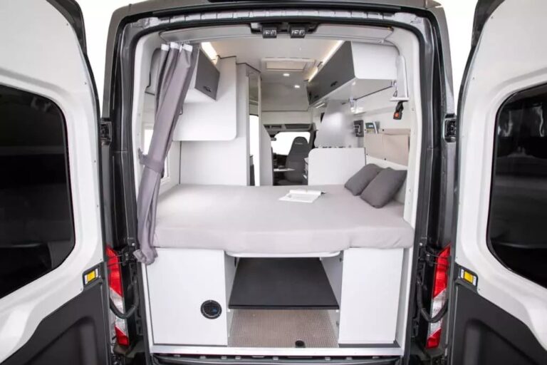 Intérieur d'un fourgon aménagé avec lit et rideau.