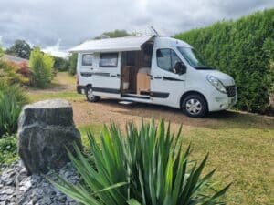 Camping-car blanc garé sur herbe verte.