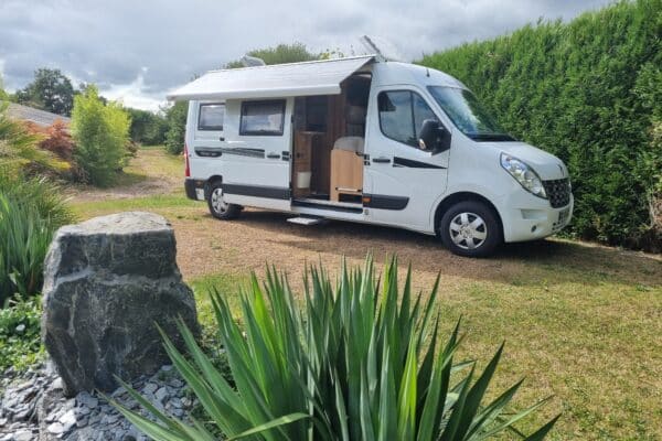 Camping-car blanc garé sur herbe verte.
