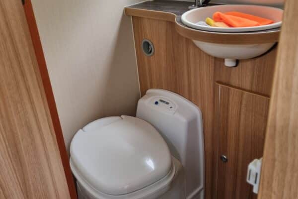 Salle de bain avec toilettes et lavabo en camping-car.
