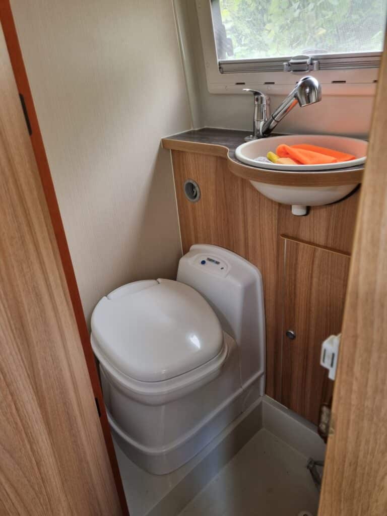 Salle de bain avec toilettes et lavabo en camping-car.