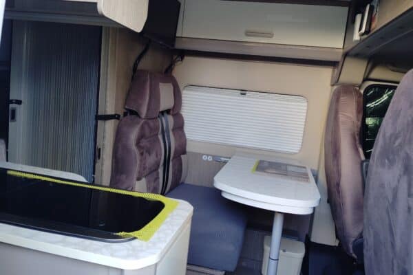 Innenansicht eines modernen Wohnmobil mit Sitzen und Tisch.
