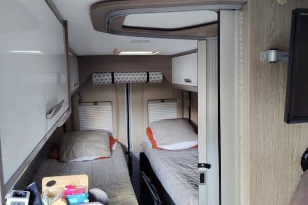 Innenausstattung Wohnmobil mit Einzelbetten und Ablagefächern.