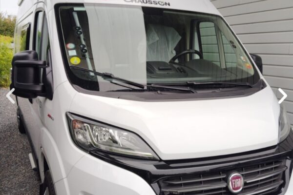 Wohnmobil weiß geparkt unter Schutzdach.