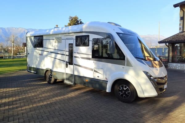 Camper bianco parcheggiato su strada lastricata.