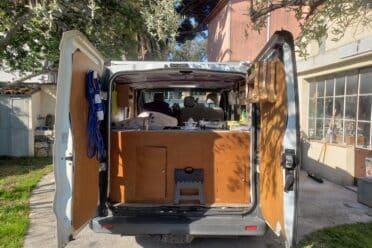 Intérieur aménagé d'un van stationné devant une maison.