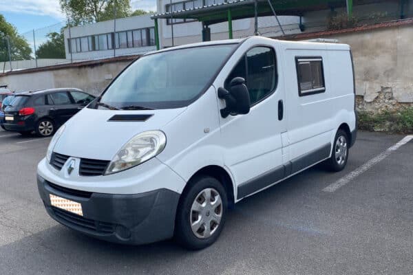 Fourgonnette blanche stationnée sur un parking extérieur.