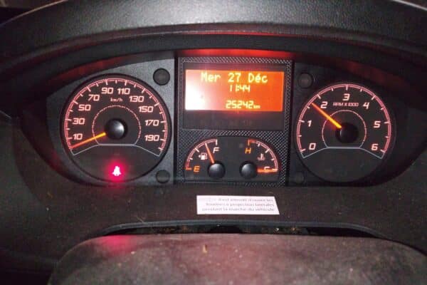 Tableau de bord de voiture avec compteurs allumés.