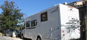 Camping-car blanc stationné près d'une maison