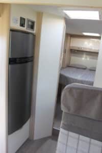 Intérieur d'un camping-car avec lit et réfrigérateur.