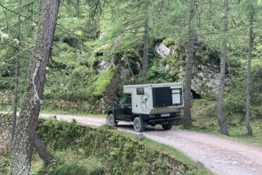Camion aménagé roulant sur chemin forestier.