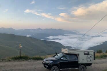 Camion sur route montagneuse, vue sur nuages bas.