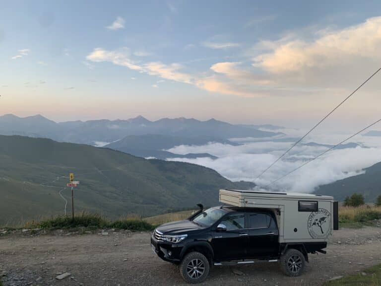 Camion sur route montagneuse, vue sur nuages bas.