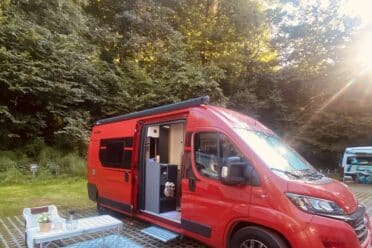 Camping-car rouge stationné en nature.