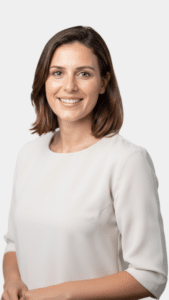 Femme souriante en chemisier blanc sur fond clair.