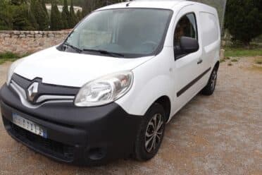 Fourgonnette blanche garée sur un chemin de gravier.