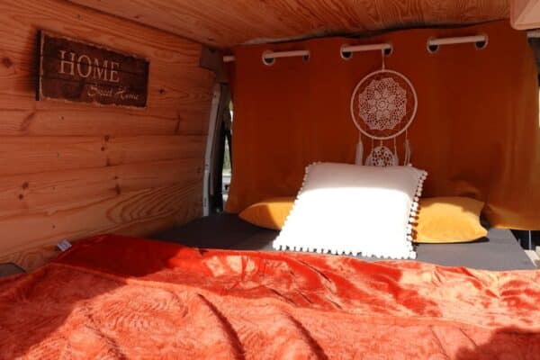 Interno del furgone con letto e decorazioni.