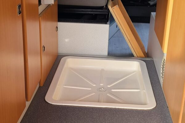 Intérieur de van aménagé avec évier, sièges.