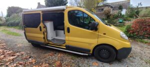 Fourgon aménagé jaune sur chemin gravillonné