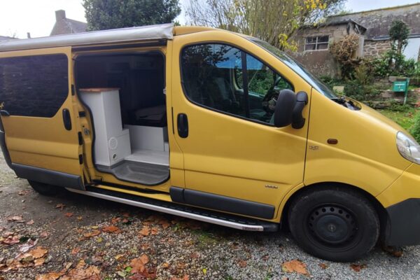 Fourgon aménagé jaune sur chemin gravillonné