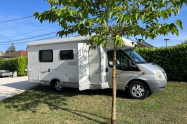 Camping-car blanc garé sous un arbre