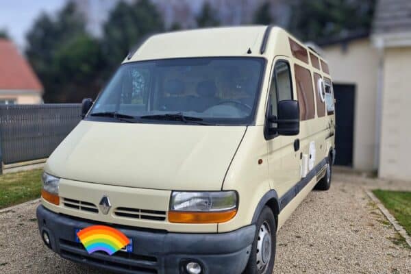 Camping-car beige garé dans une cour gravillonnée