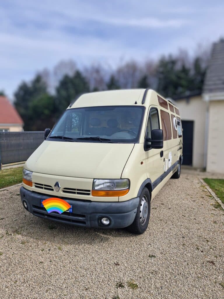 Camping-car beige garé dans une cour gravillonnée