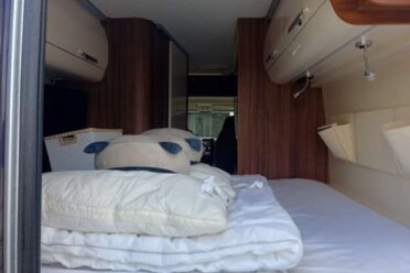 Innenausstattung von Wohnmobil mit Bett und Ablagen aus Holz