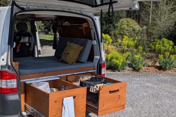 Van aménagé avec tiroirs ouverts et lit