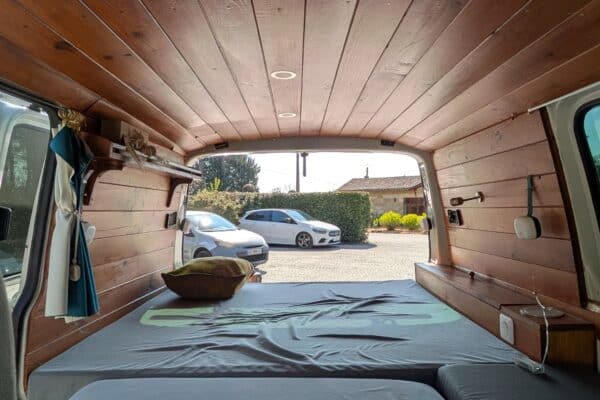 Intérieur aménagé d’un van avec lit et plafond en bois