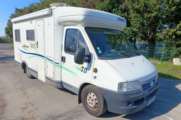 Camping-car blanc stationné en extérieur par temps ensoleillé