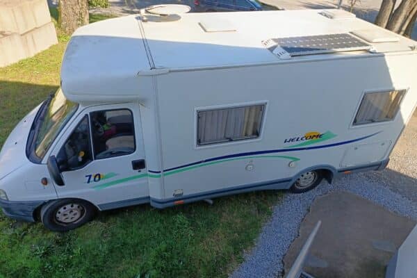 Camping-car blanc garé près d'une maison