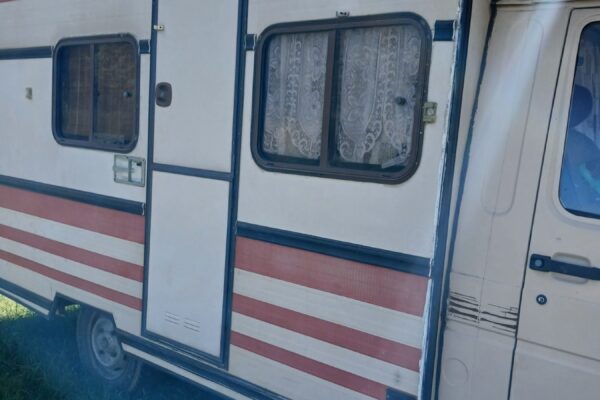 Caravane blanche à bandes rouges stationnée sur herbe