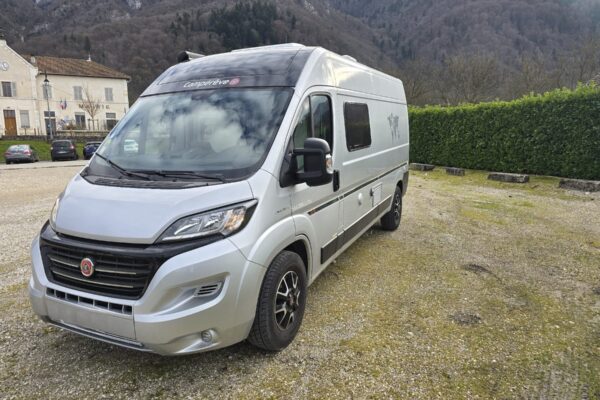 Van aménagé gris stationné près de montagnes