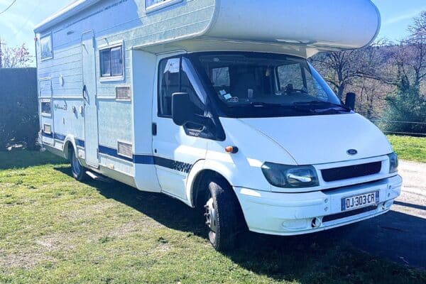 Camping-car blanc stationné sur pelouse ensoleillée