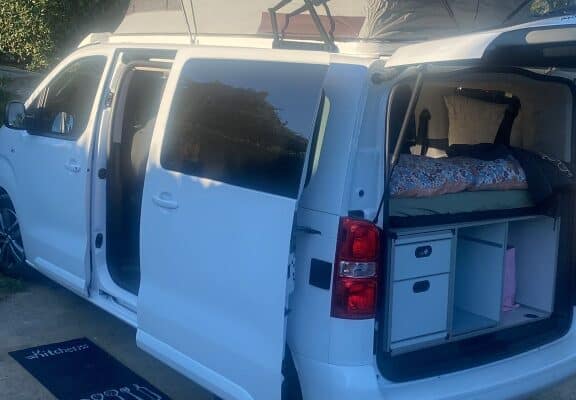 Van aménagé blanc avec toit relevable ouvert