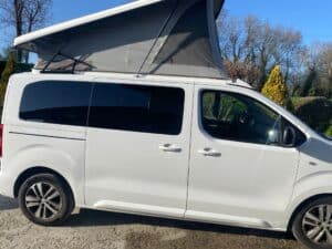 Van aménagé blanc avec toit relevable ouvert