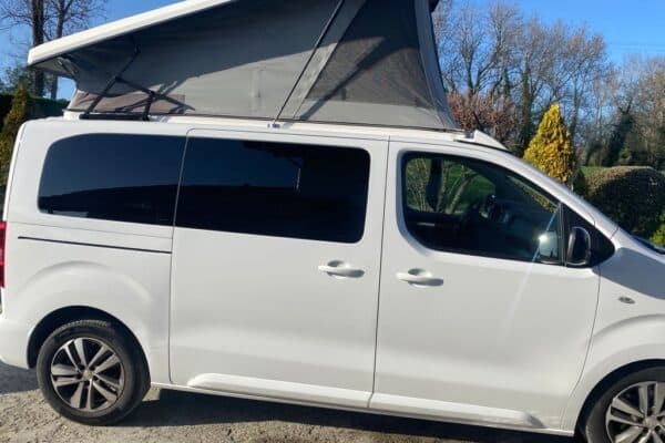 Van aménagé blanc avec toit relevable ouvert