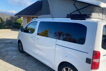 Van aménagé blanc avec toit relevable ouvert