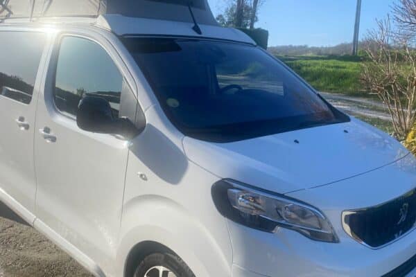 Van aménagé blanc avec toit relevable ouvert