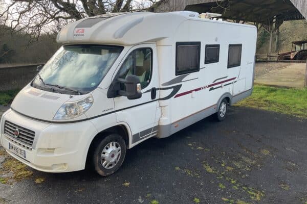 Camping-car blanc stationné près d’une grange